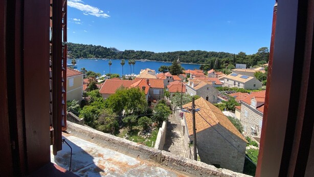 Un pueblo costero con edificios de techo rojo, un cielo azul despejado y vista al mar.