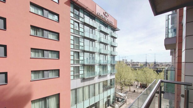 Monikerroksinen rakennus, jossa on suuri ja näkyvästi esillä oleva «Crowne Plaza» -kyltti, suuret ikkunat ja selkeästi erottuva ulkotila, jossa on istuimia.
