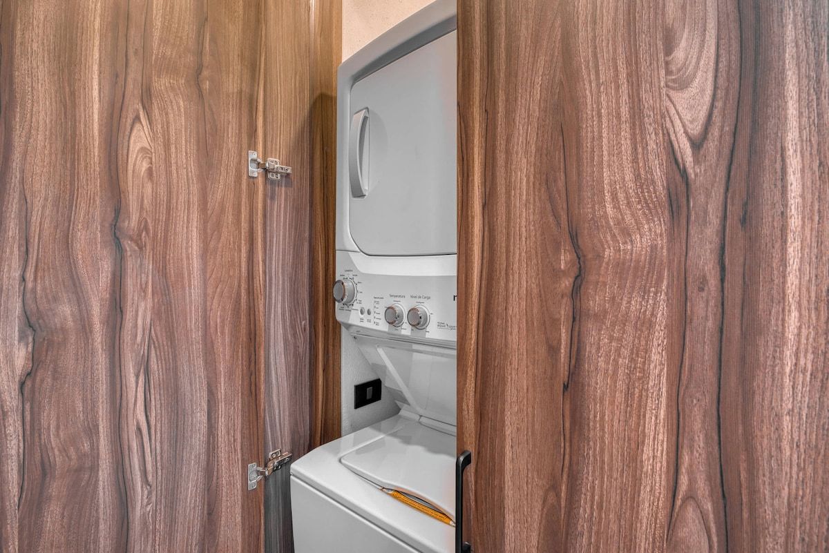 A compact laundry room with a washing machine and dryer, enclosed by wooden doors.
