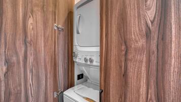 A compact laundry room with a washing machine and dryer, enclosed by wooden doors.