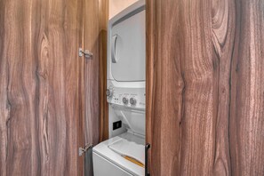 A compact laundry room with a washing machine and dryer, enclosed by wooden doors.