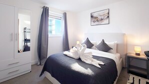 Habitación de hotel con cama, armario, mesita de noche y ventana con cortinas.