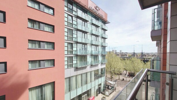 Un edificio de varios pisos con un llamativo letrero de 'Crowne Plaza', amplias ventanas y un área de estar al aire libre.