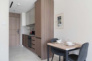 A modern kitchen with wooden cabinets, a dining table with chairs, and a framed picture on the wall.