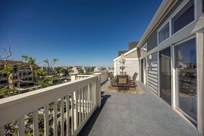 Un balcon avec une balustrade blanche, une table avec des chaises et une vue sur les maisons voisines.