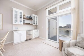 Una cucina moderna con mobili bianchi, forno integrato e un'ampia porta scorrevole in vetro che dà su un balcone con vista sulla città.
