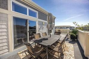 Une terrasse avec une table et des chaises, un parasol et une vue sur un immeuble.