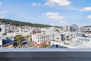A cityscape with a mix of modern and traditional buildings, a clear sky, and a hilly background.