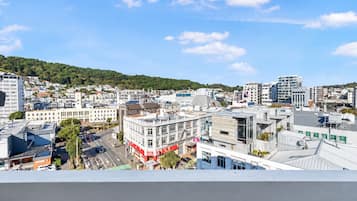 A cityscape with modern buildings, a clear sky, and a hilly background.