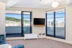 Una habitación moderna con ventanas amplias, televisión de pantalla plana y radiador.