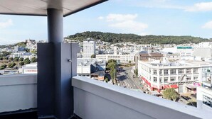 A cityscape view from a balcony with a concrete pillar, buildings, and a hill in the background. - 1BR Studio in Te Aro - City Lookout (Wellington)