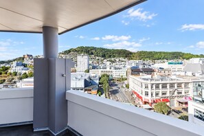 Een balkon met uitzicht op een stadsgezicht, gebouwen en een heuvel in de verte.