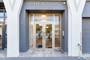 De ingang van Chevron Suites met een glazen deur en een bord erboven.