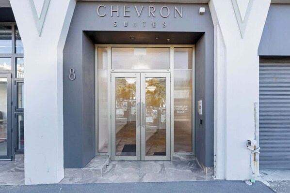 The entrance to Chevron Suites with a modern design, including a glass door and a number '8' sign.