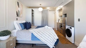 Een moderne slaapkamer met een bed, nachtkastje en een groot raam.