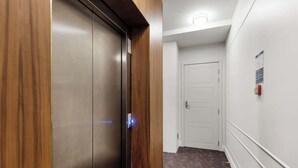 A hallway with a wooden door and a white door at the end. - Cityview Studio + Kitchen | Wellington CBD (Wellington)