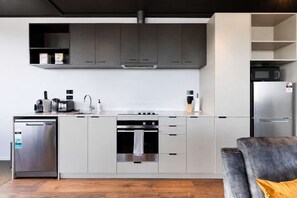 A modern kitchen with grey cabinets, a stainless steel dishwasher, an oven, and a built-in microwave.