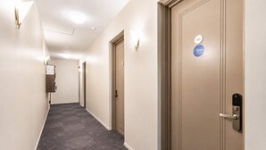 Hotellin käytävä, jossa on matto lattialla, ovi, jossa on avainkortinlukija, ja kyltti, jossa on merkitty huoneen numero 402.
