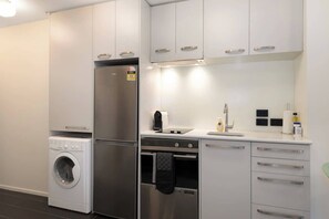 A compact kitchen with a washing machine, a refrigerator, an oven, and a sink. - Mt Victoria Studio - Kitchen, Bath Tub, Sleeps 2 (Wellington)