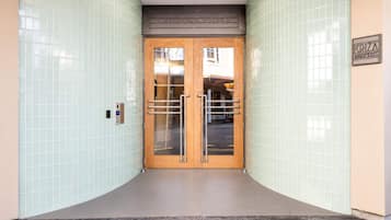 Entrada de un edificio con un muro de azulejos, una puerta doble con panel de vidrio y un letrero que indica 'CRANMEIR SQUARE'.