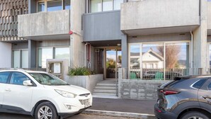 Um edifício moderno com fachada de concreto, grandes janelas e portão fechado.