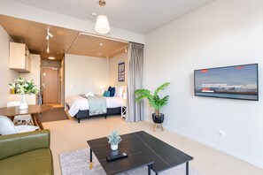 Une chambre d’hôtel moderne équipée d’un lit, d’un coin repas, d’une télévision et d’une plante en pot.