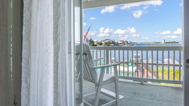 Ein Balkon mit weißem Stuhl und Blick auf eine Marina, bewölkter Himmel.
