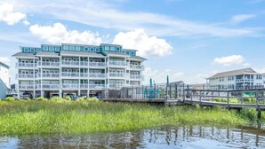 Ein mehrstöckiges Hotel mit Balkonen, einem Anleger und Blick auf das Wasser.