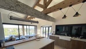 A modern kitchen with a large island, wooden cabinets, a built-in oven, and a large window offering a scenic view. - Villa with exceptional sea view and direct beach access (La Seyne-sur-Mer)