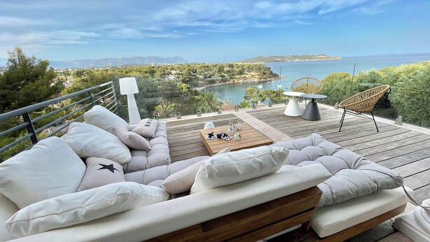 A balcony with a sofa, a table, and chairs overlooking a scenic view of a lake and mountains. - Villa with exceptional sea view and direct beach access (La Seyne-sur-Mer)
