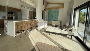 A modern kitchen with a central island, bar stools, and a dining area with a sofa and table. - Villa with exceptional sea view and direct beach access (La Seyne-sur-Mer)