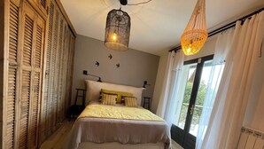 A bedroom with a bed, a hanging light fixture, a window with curtains, and a patterned rug. - Villa with exceptional sea view and direct beach access (La Seyne-sur-Mer)