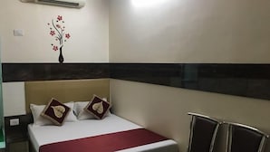 Habitación de hotel con cama, un muro decorativo, aire acondicionado y una zona de estar.