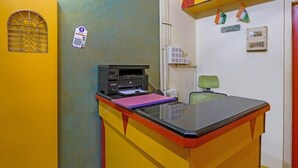 Un escritorio con una impresora, una carpeta rosa y una silla verde.