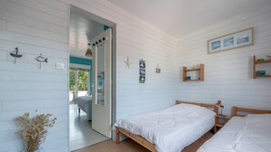 A bedroom with two wooden beds, a white vase with dried flowers, and a door leading to a balcony. - Sea view, beach 50m away, House for 4, terrace (La Plaine-sur-Mer)