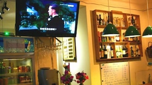 Un área de bar con un televisor montado sobre la barra, un tablero de menú y estantes con botellas.