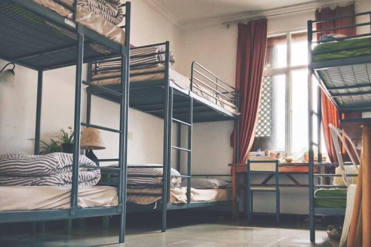Un dormitorio con literas, un escritorio y una ventana con cortinas.