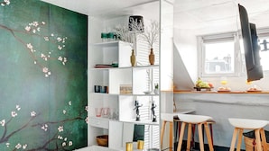 Een moderne slaapkamer met een groot bed, een bureau met een computer en een groene muur met een boommotief.