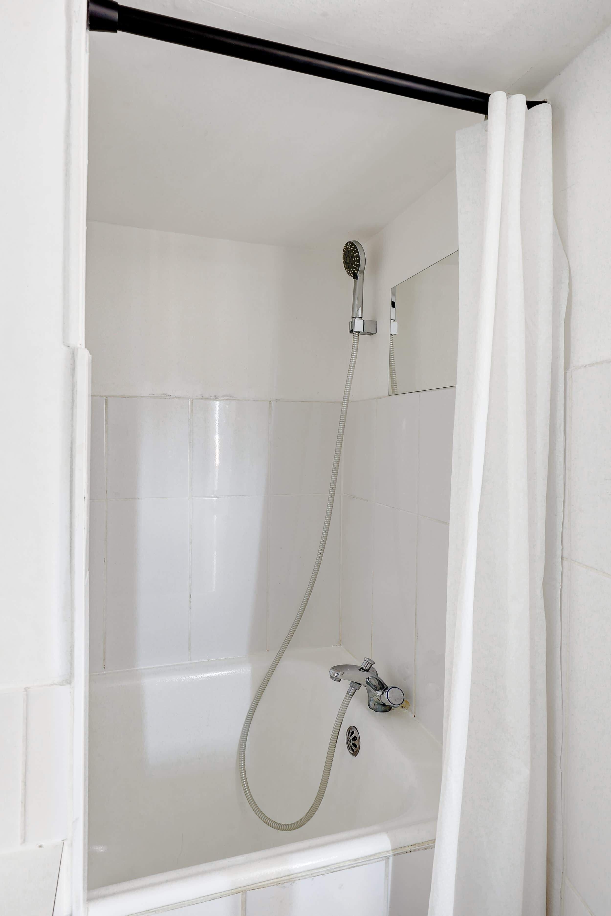 Une douche équipée d’un pommeau de douche à main, d’un robinet mural et d’un espace de douche délimité par des parois en verre.