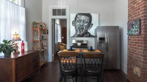 Une cuisine avec une table à manger, des chaises, un réfrigérateur et un tableau accroché au mur.