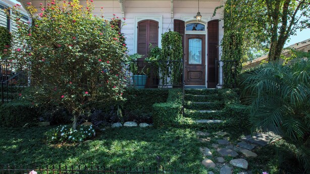 Un jardin bien entretenu, avec un chemin de pierres menant à une maison dotée d’une porte marron et d’une plaque portant le numéro 28.