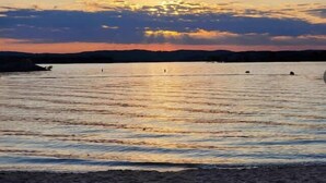 A beach with calm waters reflecting the sunset. - Near SDC + Strip | Patio | Pool | Family Friendly (Branson)