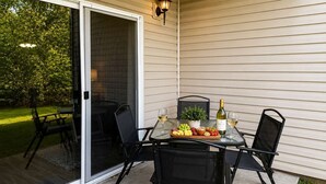 An outdoor patio with a table set for two, featuring a bottle of wine, glasses, and a fruit platter. - Near SDC + Strip | Patio | Pool | Family Friendly (Branson)