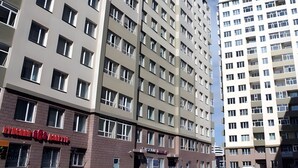 Ein mehrstöckiges Hotel mit modernem Design, erkennbar an der gut sichtbaren Beschilderung für 'Hotel & Apartments'.