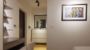 Ein modernes Schlafzimmer mit einem Bett, einem Schreibtisch mit Stuhl, einer Kommode und einem gerahmten Gemälde an der Wand.