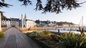A wooden boardwalk leading to a marina with boats, a church, and buildings in the background.