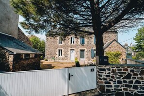 Stately building with a traditional facade, surrounded by a secure perimeter and a large tree.