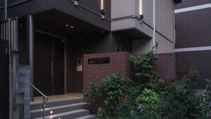 Une entrée moderne, avec un escalier menant à une porte, le tout entouré de verdure.