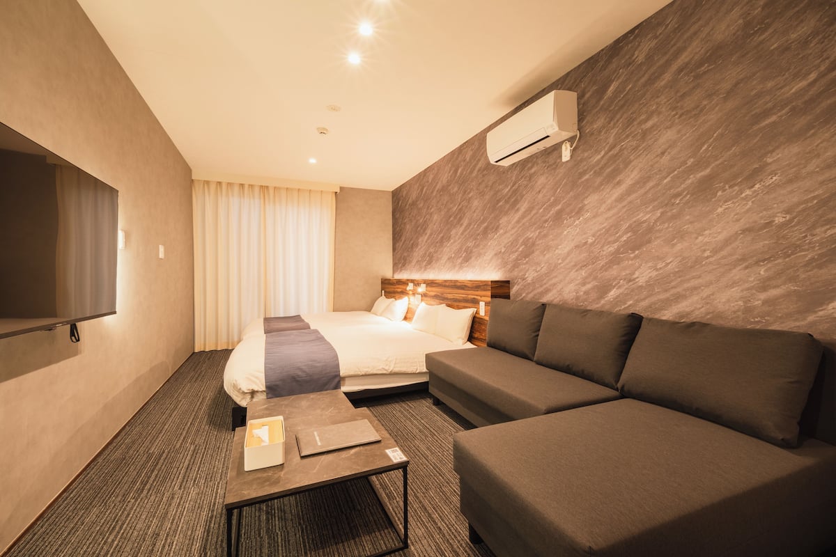 Une chambre d’hôtel équipée d’un lit, d’un canapé, d’une table basse et d’un téléviseur à écran plat.