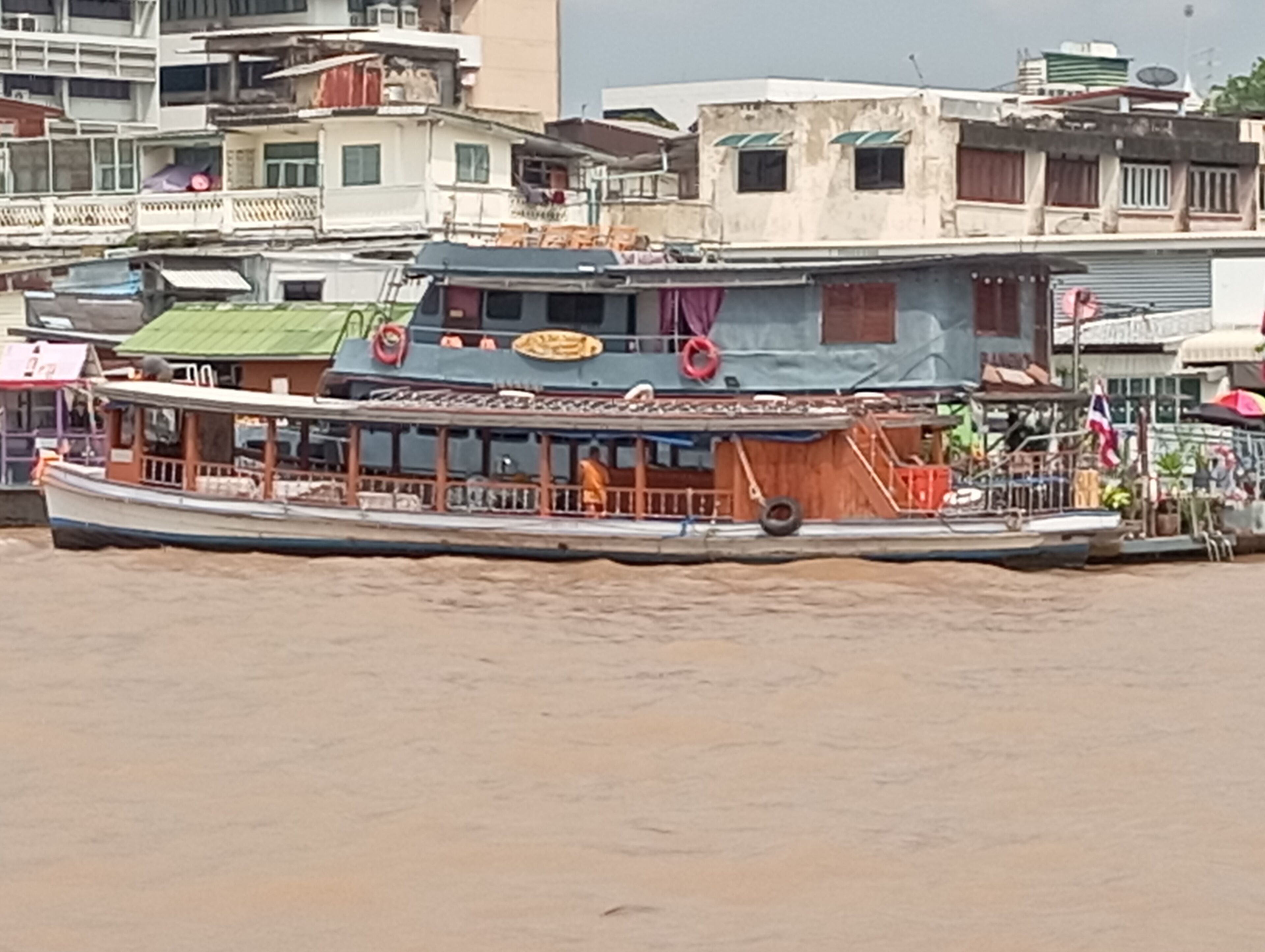 A boat docked at a river with a building in the background.